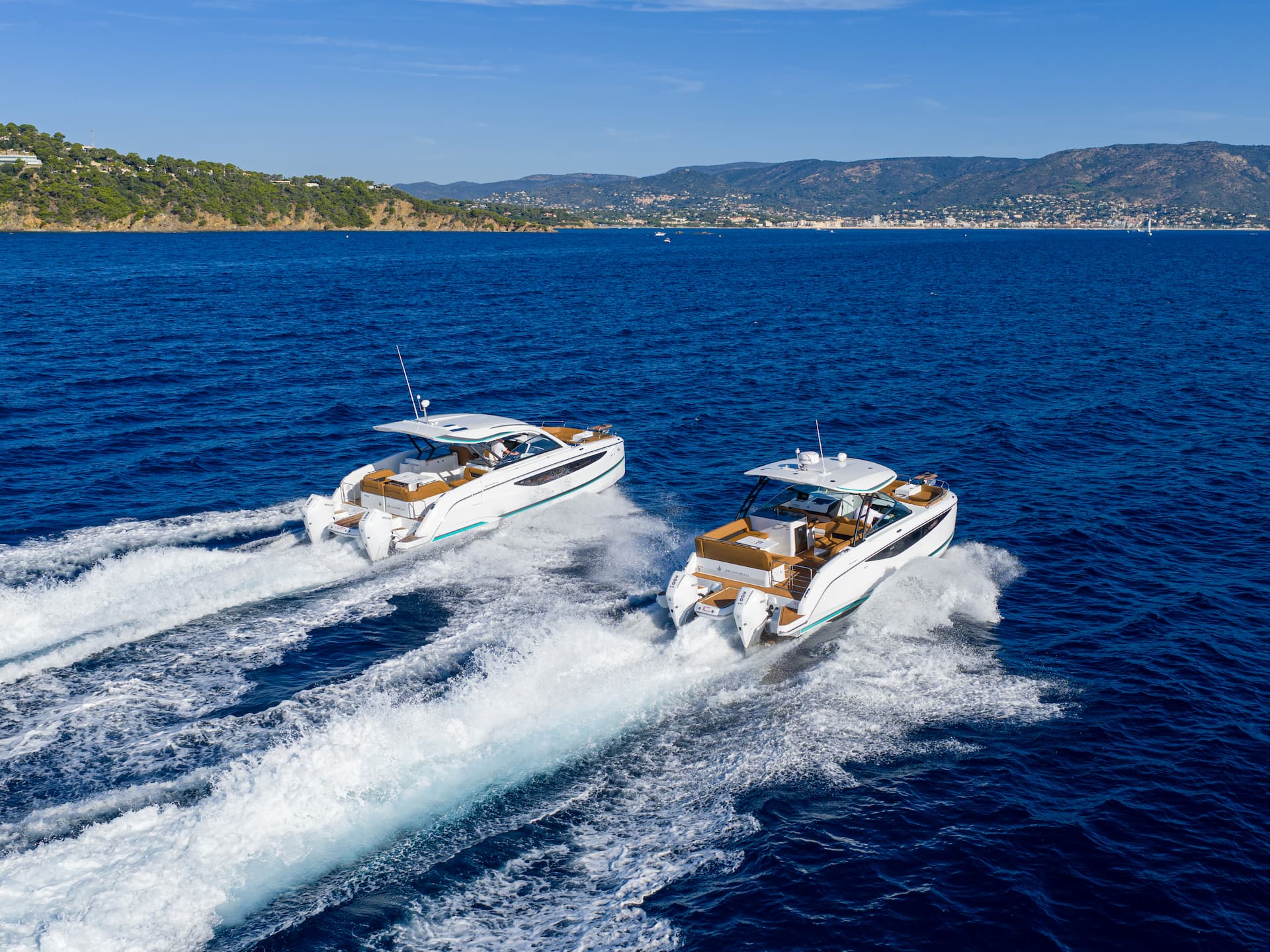 Two Jeanneau motorboats cruising together on blue water